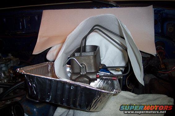 Master cylinder with brake lines connected, sitting in a foil pan