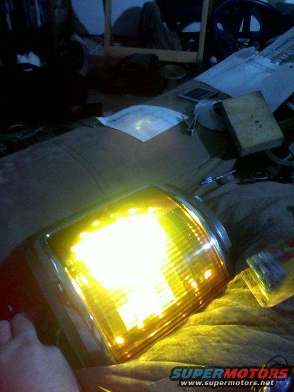 close-up of a yellow car turn signal assembly with internal lights illuminated