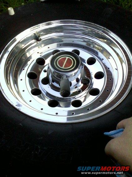 Chrome wheel hubcap with red and black emblem on a tire