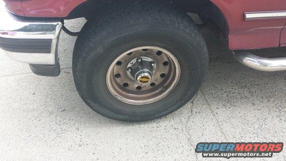 Maroon SUV wheel with chrome trim and a portion of the fender and bumper
