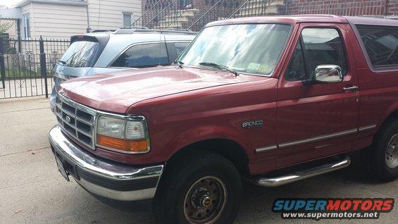 Red 1996 Ford Bronco parked on street, silver SUV behind it