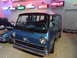 1971 Ford Ranchero - A blue van is displayed indoors, with neon signs for various car brands on the wall behind it.
