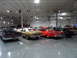 1971 Ford Ranchero - A collection of vintage automobiles are displayed indoors under bright lighting.