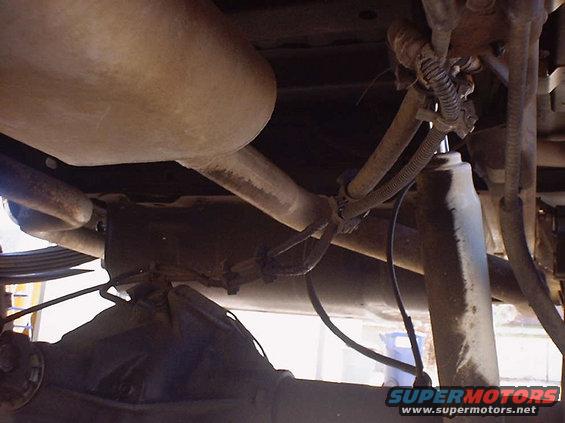 Underside view of vehicle exhaust pipe, muffler, shock absorber, and rear differential