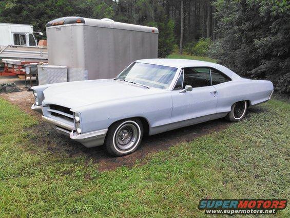 1967 Pontiac Catalina, primer gray, parked outside next to a trailer