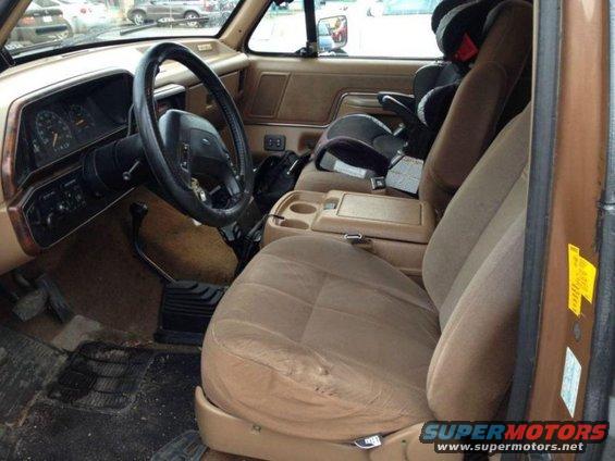 Brown interior of a 1987 Ford Bronco with a child seat behind the passenger seat