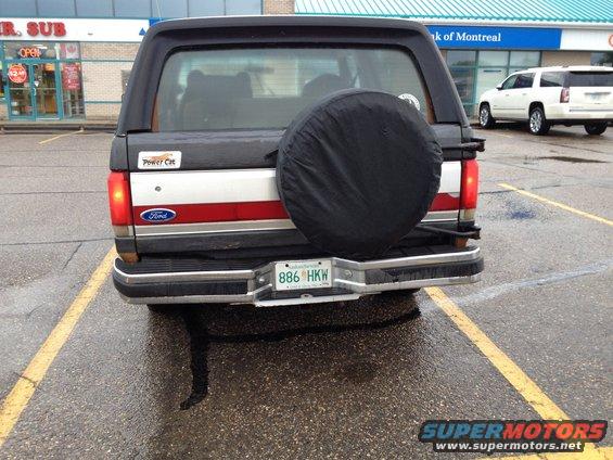 Black Ford Bronco rear view with spare tire cover, red and white stripe, and license plate 886 HKW