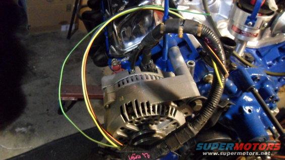 Engine alternator with blue painted block and chrome accents. Wires are connected