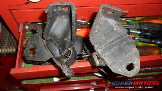Two old rubber engine mounts, one cracked and torn, sitting in a red toolbox drawer with tools