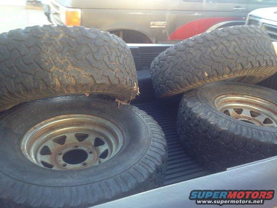 Four off-road tires stacked in a truck bed