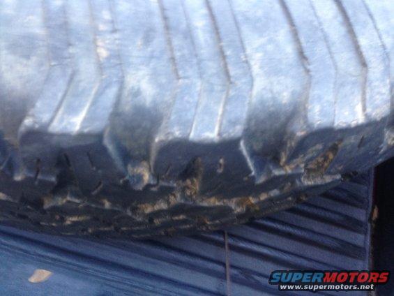 Close-up of a large tire tread with some damage on the sidewall