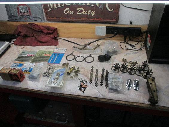 Assorted hardware and tools including Bosch blades, drawer pulls, and hinges on a workbench