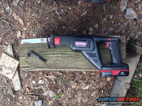 Black Craftsman reciprocating saw with red accents and a lithium-ion battery pack rests on a wooden plank