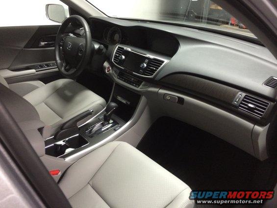 Car interior with light gray leather seats, dashboard, steering wheel, and center console. Wood trim accents visible