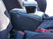 1993 Mazda MX-3 - Close-up of a car's interior, focusing on the center console armrest and seatbelt mechanism.