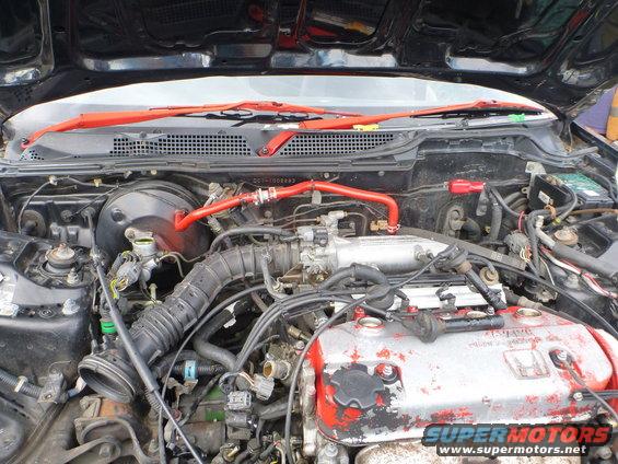 Engine bay with red accents on hoses and strut bar. Honda engine cover is visible
