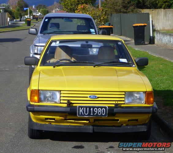 Yellow Ford sedan with KU 1980 license plate parked on street, front view