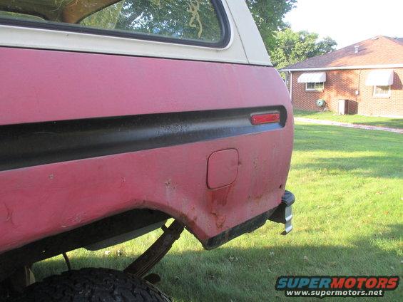 Red 1979 Ford Bronco rear quarter panel with black trim and a fuel door