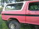 1979 Ford Bronco - Side view of a red and white 1979 Ford Bronco, showing its distinctive body style and BFGoodrich tires.
