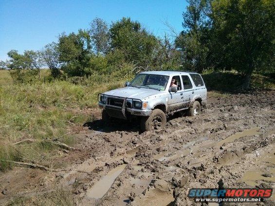 Silver Toyota 4Runner stuck in mud, front bumper guard visible, driver inside