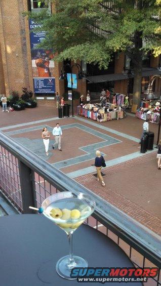Martini with olives in foreground, people and market stalls in background