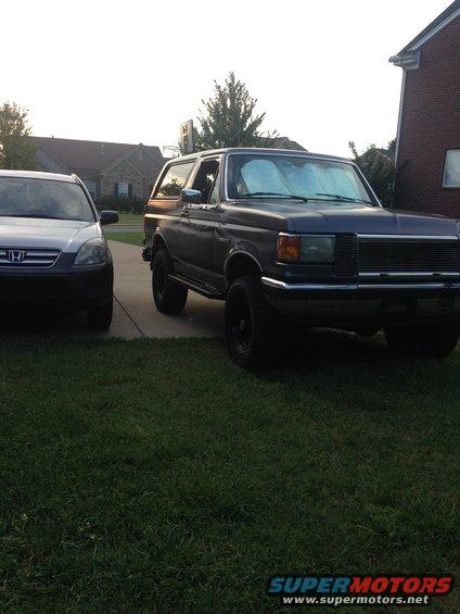 Dark blue 1990 Ford Bronco parked on driveway next to a silver SUV