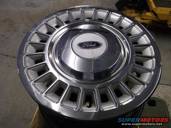 Chrome and silver Ford hubcap with rectangular cutouts and a central Ford logo