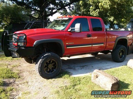 Red pickup truck with black grille guard and large tires parked outside