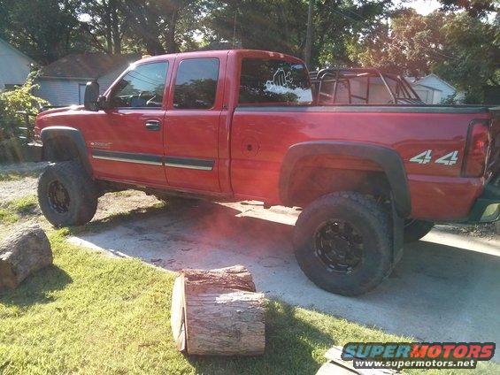 Red pickup truck with a roll cage in the bed, lifted suspension, and off-road tires