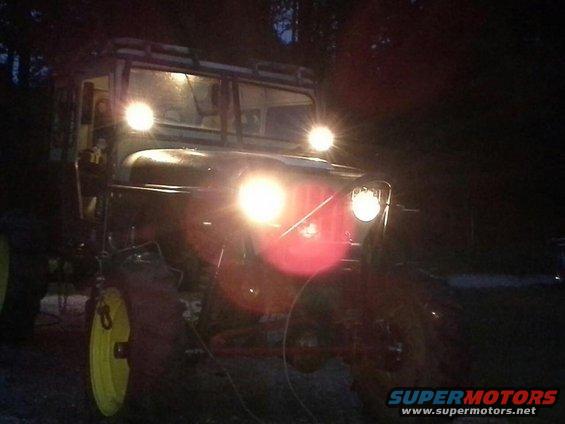 Off-road vehicle with bright headlights on, seen at night. Yellow wheel hubs are visible
