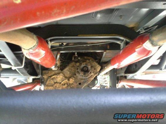 Undercarriage view of a vehicle's transfer case and dual exhaust pipes, one pipe is red