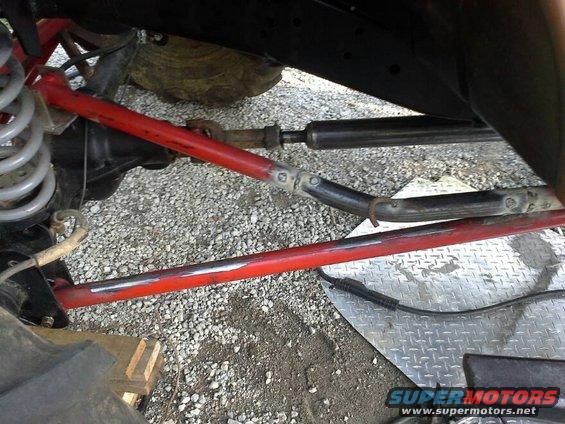Close-up of red suspension components and steering linkage on a modified off-road vehicle