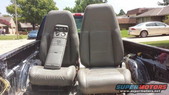 Two bucket seats and a center console with climate controls are in the bed of a pickup truck