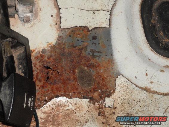rusted metal panel near hood release lever
