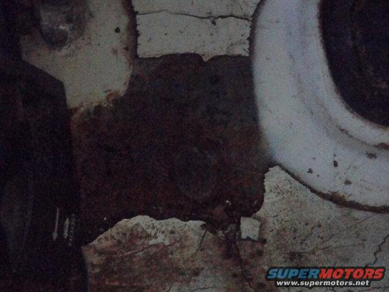 Close-up of rusted metal with white paint chipping off, showing a curved white pipe