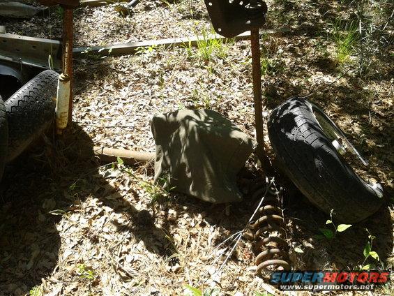 Scrap pile with two tires, a spring, and metal objects on the ground