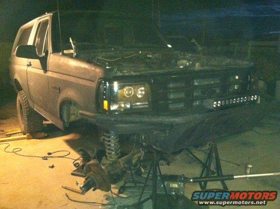 1995 Ford Bronco with hood open, front end disassembled on jack stands