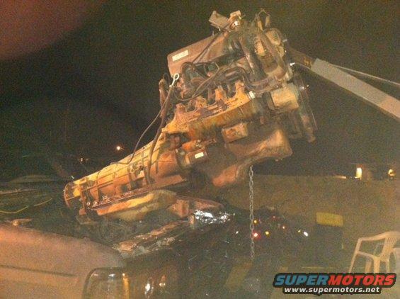Engine and transmission assembly suspended by a crane over a vehicle