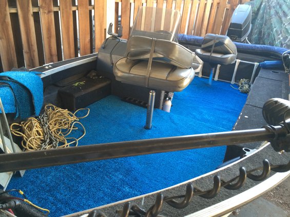 Boat interior with blue carpet, two seats, ropes, and a trolling motor