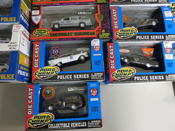 Stack of Road Champs die-cast police car models in boxes, including Chevrolet Suburban and Jeep Grand Cherokee