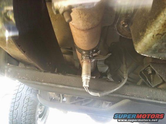 Close-up of an oxygen sensor attached to a vehicle's exhaust pipe