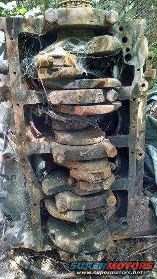 rusted engine block showing crankshaft and connecting rods, covered in cobwebs