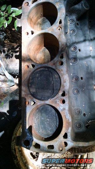 Engine block with three pistons visible, showing rust and wear