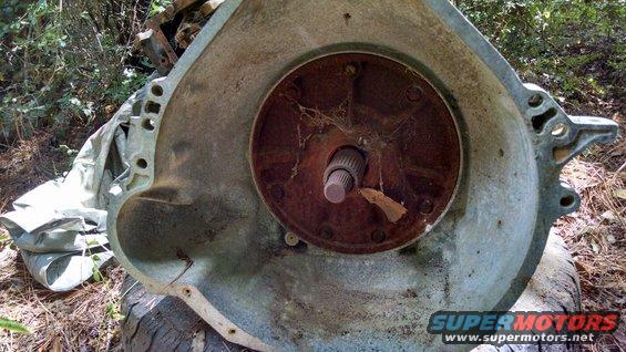 Transmission bell housing with splined shaft visible. Outdoors, some foliage in background
