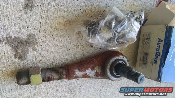 Rusty tie rod end with a nut and a plastic bag of hardware next to an AutoDrive parts box