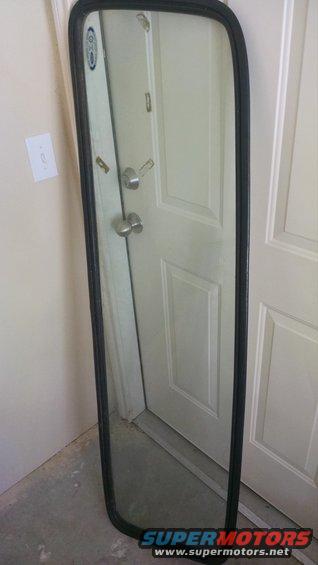 Side mirror assembly with black trim, reflecting a doorway