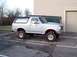 1990 Ford Bronco - This lifted Ford Bronco is parked next to a trailer in a parking lot.
