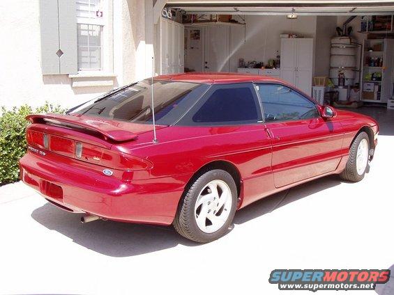 Red 1995 Ford Probe parked in a driveway with the garage door open