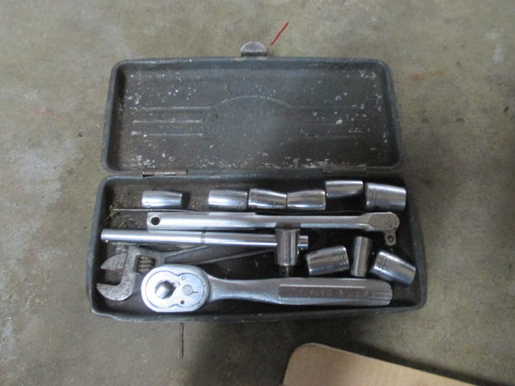 Metal toolbox open, showing a socket wrench set with various sockets and an adjustable wrench