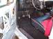 1990 Ford Bronco - The interior of a 1990 Ford Bronco shows its distinctive black and red seats, manual transmission, and exposed door panel.